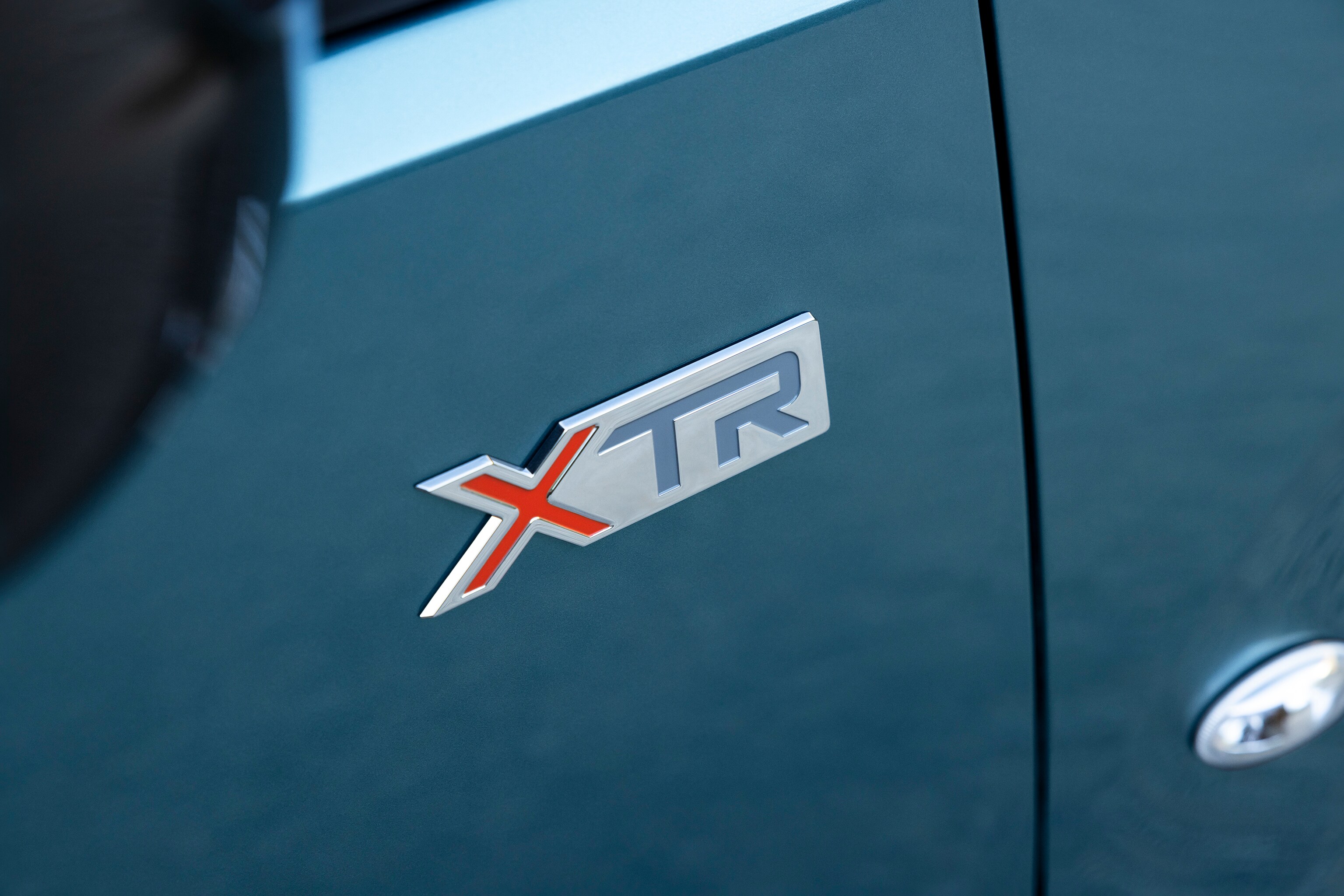 Vue détaillée du badge de ë-Berlingo XTR avec design distinctif, la qualité, la durabilité et une identité de modèle renforcée
